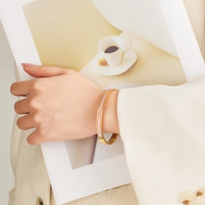 Close-up of golden stainless steel bracelet featuring inlaid pink crystals on wrist