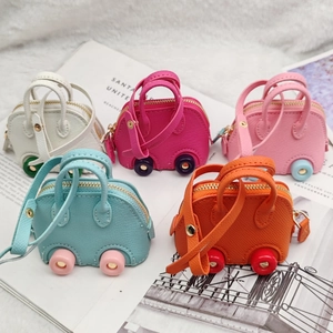 Top view of five colorful mini car-shaped coin purses on a magazine and plush rug