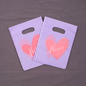 Detail of purple striped gift bag with pink hearts and Merci text for boutique shopping