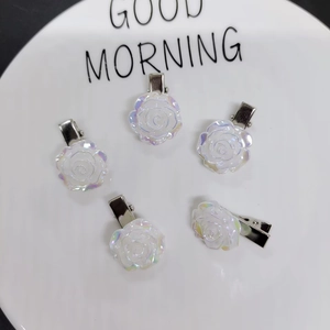 Detail of five iridescent camellia flower hair clips on a white ceramic plate