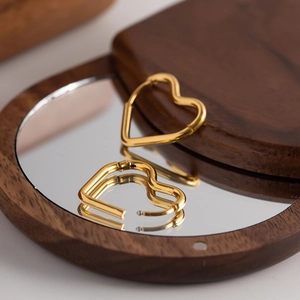 Elegant 18K gold plated titanium steel heart hoop earrings on a wooden mirror