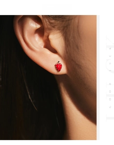 Macro view of S925 silver red strawberry stud earrings with green leaf details