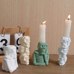 Three-tiered skull and thinker skeleton candle holder mold set with lit pillar candles