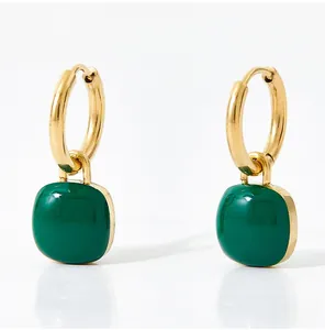Detail of gold hoop earrings with glossy green enamel square pendant on white background