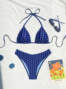 Dettaglio del bikini blu a pois con top a fascia su sfondo di tessuto bianco puro