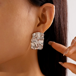 Macro side view of silver irregular geometric earrings with a crumpled metallic texture