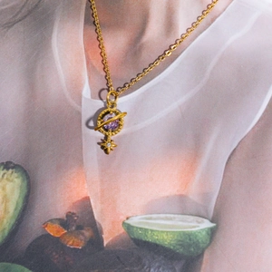 Detail of 18K gold necklace featuring a purple gemstone Saturn and zircon star pendant