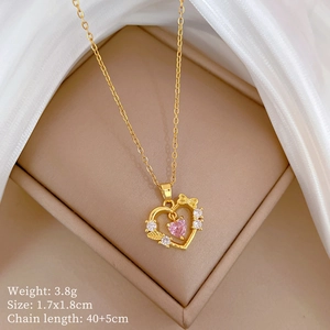 Close-up of gold heart bow necklace with pink stone and small diamonds on beige leather