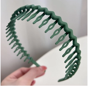Detail of dark green non-slip wave headband with matte plastic teeth for hair styling