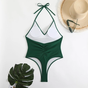 Close-up of deep green halter swimsuit with v-neck, pleats, and summer beach accessories