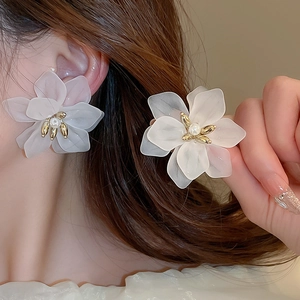 Elegant white matte flower stud earrings with pearl and gold accents on model