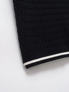 Detail of black knit polo shirt showing white stripe trim and textured cable knit pattern