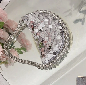 Detail of silver sequined evening bag with sparkling crystal trim on a mirror surface