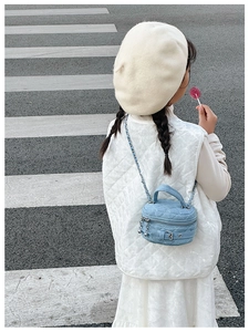 Girl wearing a denim quilted box bag with chain strap and buckle details on the street