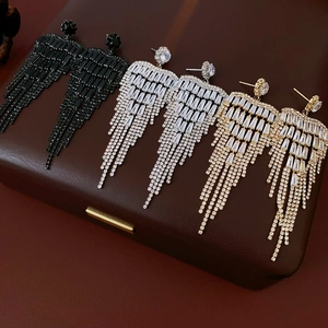 Macro view of long tassel cubic zirconia earrings in black, gold, and silver finishes