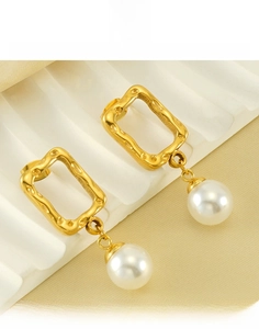 Detail of titanium steel gold earrings with rectangular studs and round pearl drops