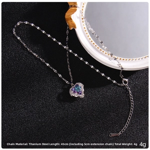 Detailed close-up of blue crystal heart pendant with white zircons on titanium steel chain