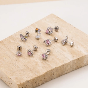 Close-up of pink zircon heart and butterfly stainless steel stud earrings on stone