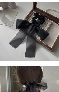 Detail showing elegant black mesh ribbon bow hair clip in a gift box and worn on hair