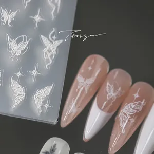 Macro detail of 3D embossed white butterfly nail stickers and French manicure effect