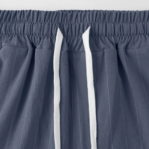 Dettaglio dei pantaloni in lino a righe blu navy con vita elastica e coulisse bianca