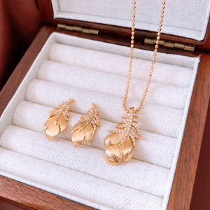 Detail of 18k gold plated feather necklace and earrings set with tiny gemstones