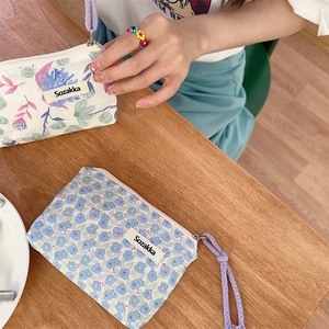 Dettaglio di pochette in tela floreale con laccetti viola su un tavolo di legno