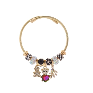 Détail macro du bracelet à breloques doré avec pendentifs cœur, ours et cristaux