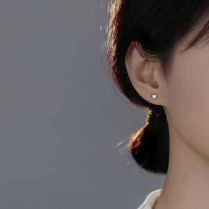 Close-up of heart-shaped S999 sterling silver stud earrings with iridescent zircon stone