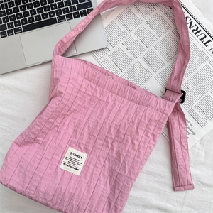 Close-up of pink pleated canvas bag showing SOZAKKA brand label and wide shoulder strap