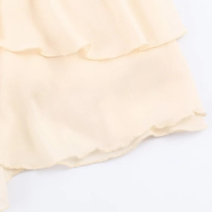 Detalle de dobladillo con volantes en vestido de gasa beige con costuras onduladas