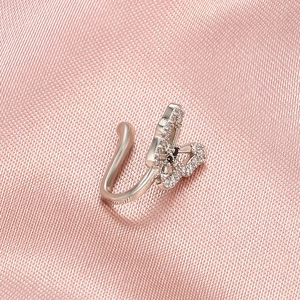 Macro detail of silver U-shaped butterfly nose clip with rhinestones on pink silk