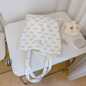 Detailed top view of light blue bow floral canvas tote bag on a white surface
