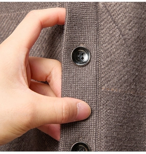 Detaillierte Nahaufnahme der dunkelbraunen Stricktextur und Knöpfe der Herren-Strickjacke