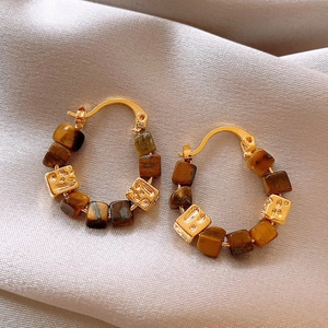 Elegant gold earrings with brown tiger eye beads on grey silk, Maillard retro style
