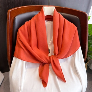 Detail of soft red cotton linen scarf draped elegantly over a white shirt and wooden chair