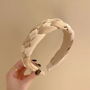 Close-up of two-tone braided headband in cream and khaki with detailed woven fabric texture