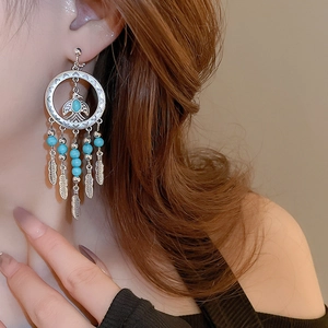 Detail of bohemian bird feather tassel clip-on earring on a model's ear