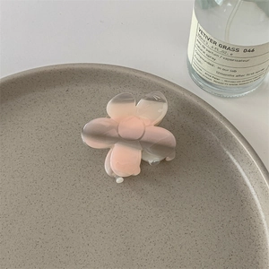 Détail d'une pince à cheveux en forme de fleur translucide avec un dégradé rose