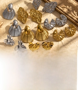 Detailed view of textured heart and geometric titanium steel earrings in gold and silver finish
