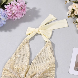 Détail d'un haut dos nu à paillettes jaune crème avec texture brillante et fines finitions