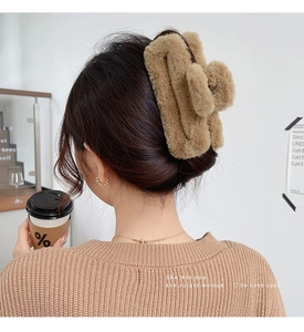 Close-up of large khaki plush hair claw clip used for styling a messy bun on thick hair