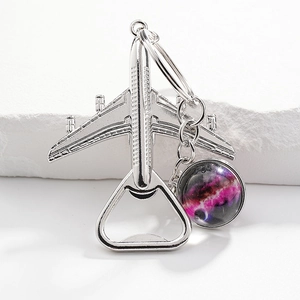 Macro shot of silver airplane bottle opener keychain with a purple nebula pendant detail