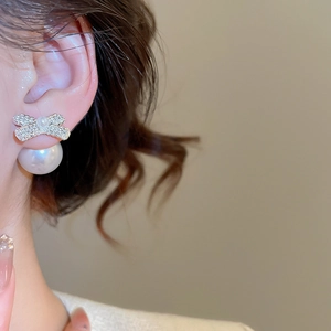 Macro detail of elegant silver bow earrings with sparkling cubic zirconia and white pearls
