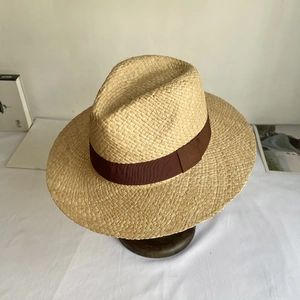 Close-up of natural beige raffia straw Panama hat with a dark brown grosgrain ribbon