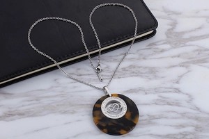 Macro view of silver stainless steel necklace with tortoise resin and crystal heart pendant