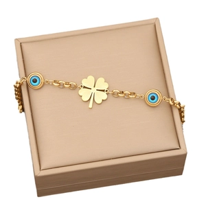 Golden clover and blue evil eye jewelry set presented in a minimalist beige gift box