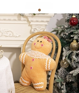 Detail of soft gingerbread man plush pillow with white lace trim on a wooden chair