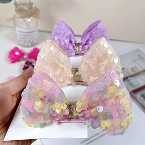 Close-up of sparkling sequin bow hair clips for girls in pink, beige and purple