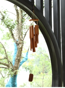 Close-up of a natural bamboo wind chime featuring multiple tubes and a wooden wind catcher